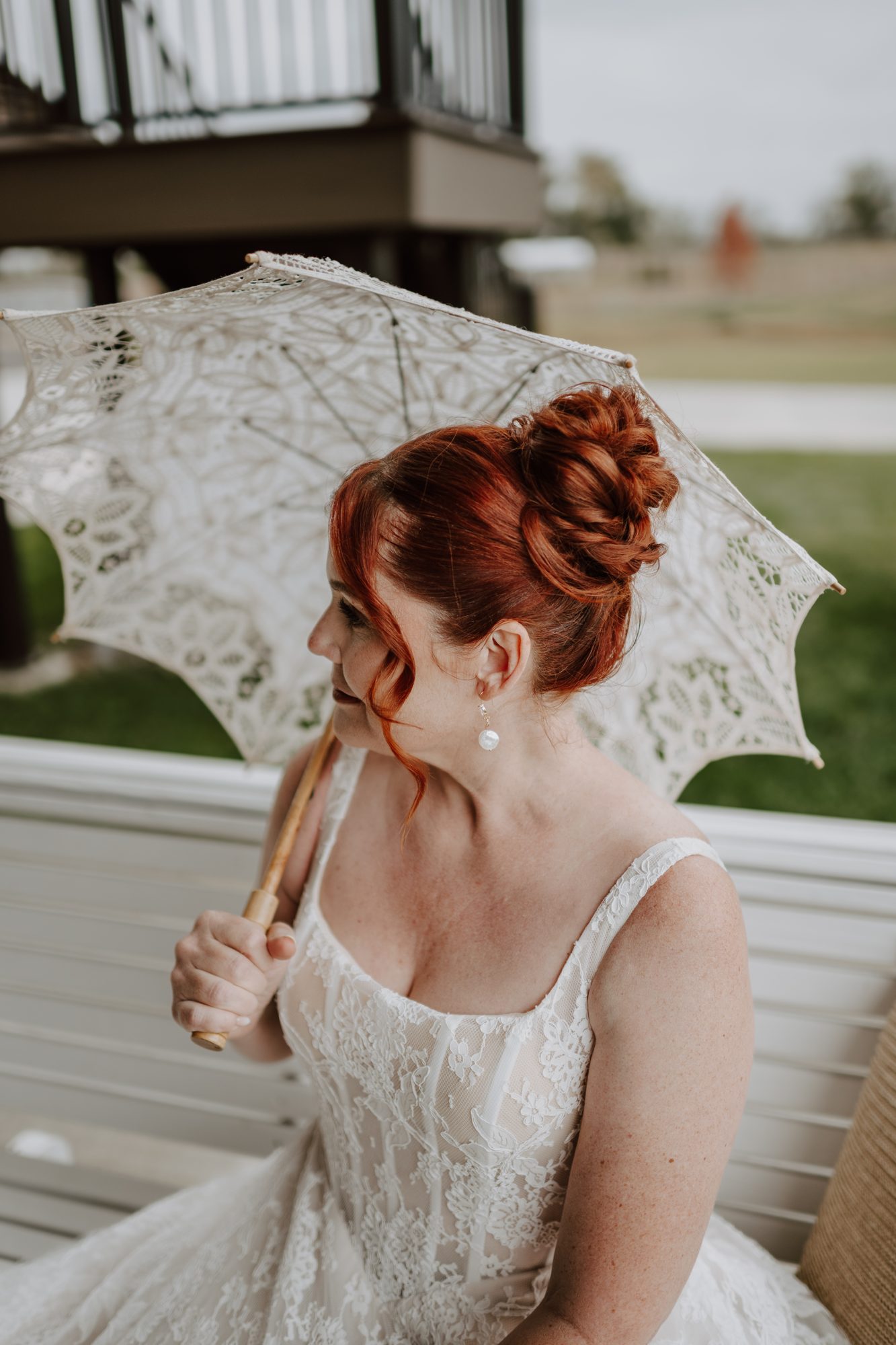 Bride with an auburn updo holding a lace parasol
