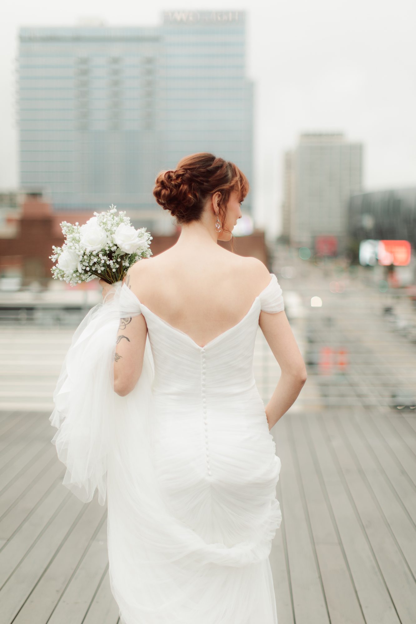 Bride in a fitted gown with a low updo, city skyline behind